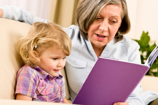 Grandmother and little girl reading book happy together at home