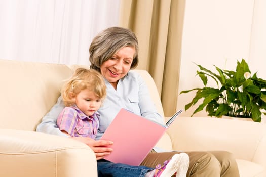 Grandmother and little girl reading book happy together at home