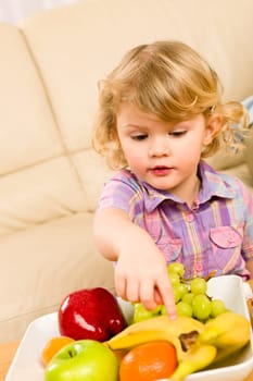 Cute little girl wants fruit pointing at banana