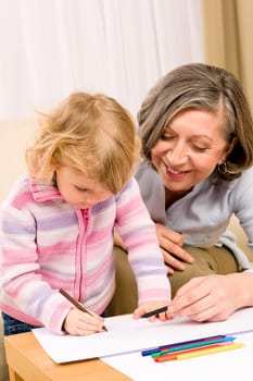 Grandmother and little girl drawing together with pencils at home
