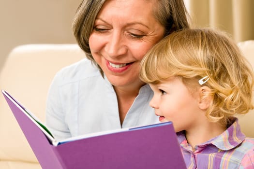 Grandmother and little girl reading book happy together at home