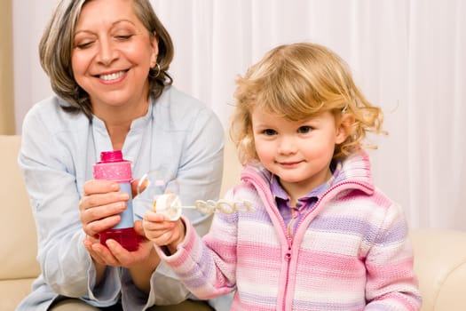 Little granddaughter with grandmother make bubble blower play happy together