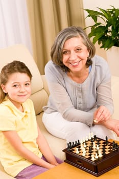 Grandmother and young girl playing chess together at home