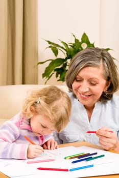 Grandmother and granddaughter drawing together with pencils at home