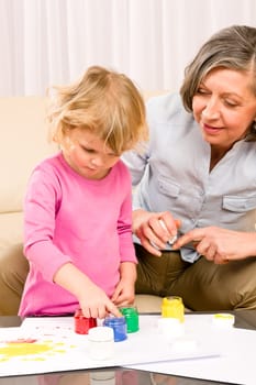 Granddaughter with grandmother play making handprints painting at home