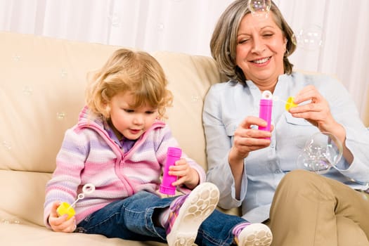Little granddaughter with grandmother make bubble blower play happy together