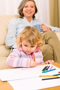 Grandmother and little girl drawing together with pencils at home