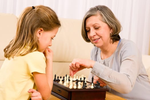 Grandmother and young girl playing chess together at home
