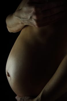 details of a pregnant woman isolated on black