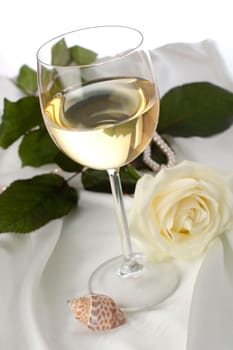 white wine with white rose on silk close up shoot