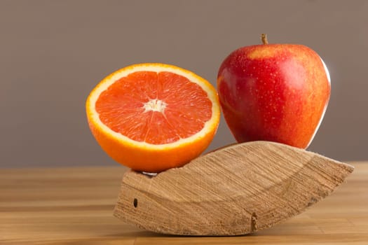 Orange and apple lying in a wooden bowl on a table