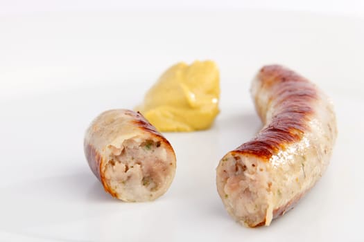 Sliced bratwurst with mustard on white background