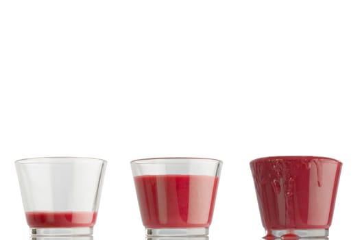 Three glasses of juice,from very little to overflowing