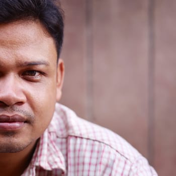 Portrait of asian 30 years old man looking at camera against brown wall. Copy space, square shot