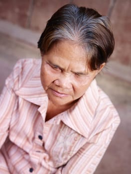 Portrait of serious senior asian woman against brown wall