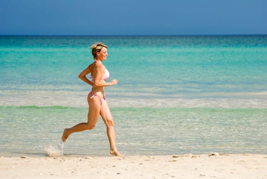 young blond woman running on the beach