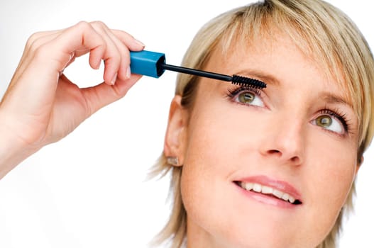 young blond woman applying mascara cose up