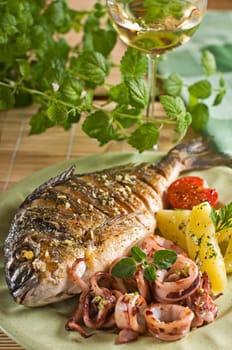 Roasted fish and squid with potatoes close up