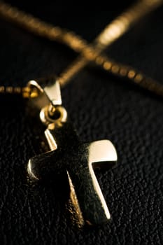 Golden jewelry cross with necklace on black fabric