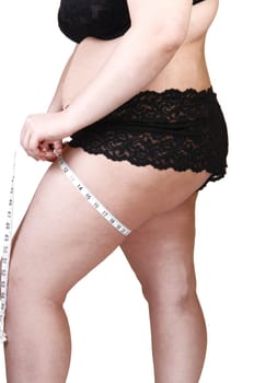 A heavy woman in black lingerie measuring her tights, showing her  butt and stomach, for white background.