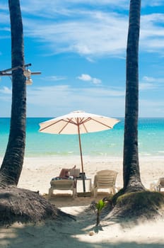 someone reading a book under a white parasol on a tropica beach