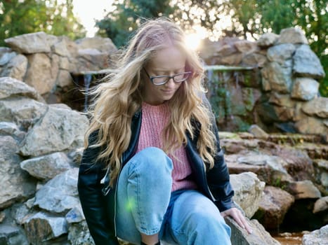 Natural Curly Blonde Woman, Albino Sitting in park, Outdoors. Lack of melanin pigment in hair and skin. A person with poor eyesight wearing glasses. Close up