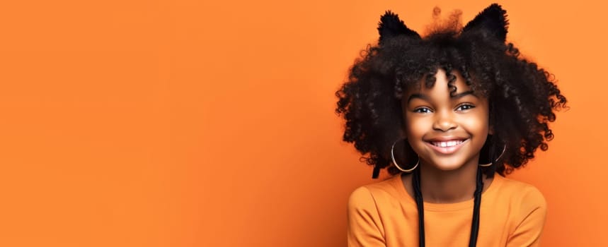 Banner of Cute african american girl in cat halloween costume looking at camera and smiling over orange background. Happy Halloween. Trick or treat