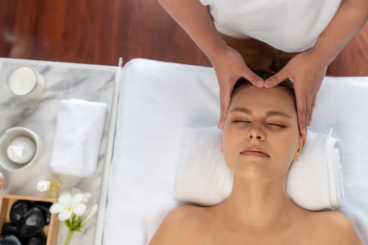 Panorama top view of woman enjoying relaxing anti-stress head massage and pampering facial beauty skin recreation leisure in dayspa modern light ambient at luxury resort or hotel spa salon. Quiescent