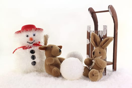 Snowman and stuffed animals having fun in winter