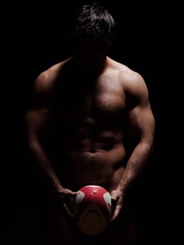 one caucasian sexy naked  man portrait holding rugby ball on studio black background