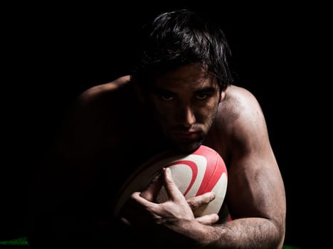 one caucasian sexy topless man portrait hugging a rugby ball on studio black background