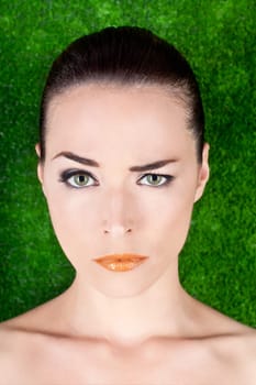 Closeup portrait of a serious beautiful woman raising an eyebrow on green background