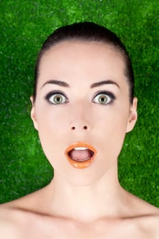 Closeup portrait of a surprised beautiful woman mouth open on green