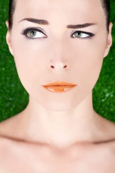Closeup portrait of a beautiful angry woman with glossy lips looking away on green background