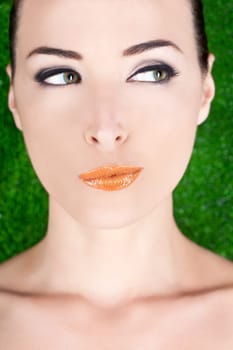 Closeup portrait of a beautiful suspicious woman looking away in studio against green