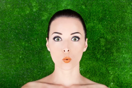 Closeup of a beautiful surprised woman beauty portrait in studio  grass background