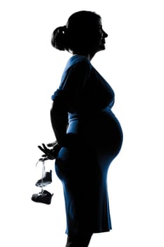 beautiful caucasian pregnant woman holding baby shoes in silhouette on studio isolated white background