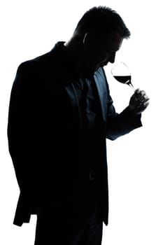 one caucasian man portrait silhouette smelling red wine glass in studio isolated white background