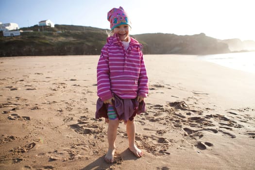 Portrait of a cute little girl standing barefoot on the beach