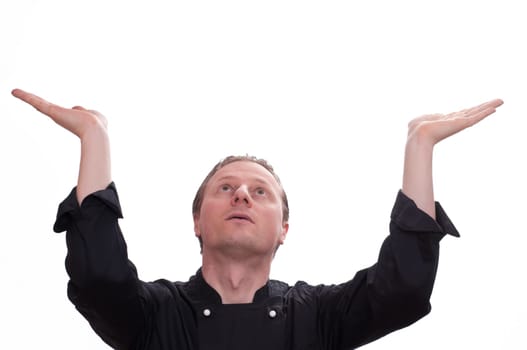 A man as a cook supports a heavy load with his hands and looks up