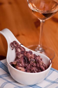 A salad of squid moscardini with herbs and a glass of wine