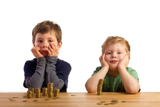 Two boys sit thoughtfully in front of money towers