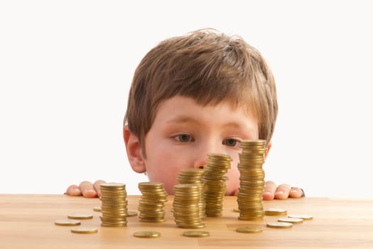Boy looking at money towers lying on a table