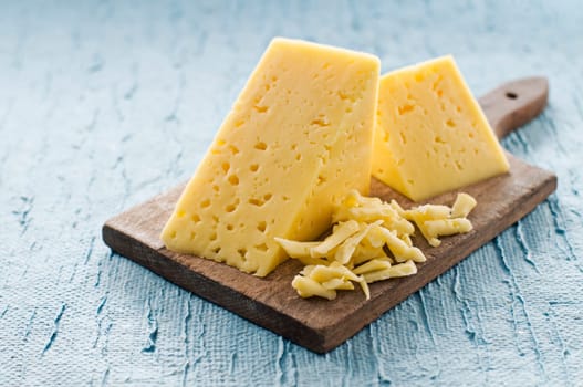 Hunch of cheese on blue background close up