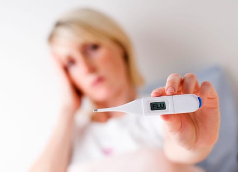 Ill woman showing thermometer close up - flu concept
