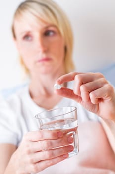 Young blond woman taking pill close up