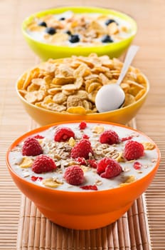 Fresh corn flakes with raspberries and milk close up