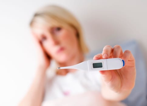 Ill woman showing thermometer close up - flu concept