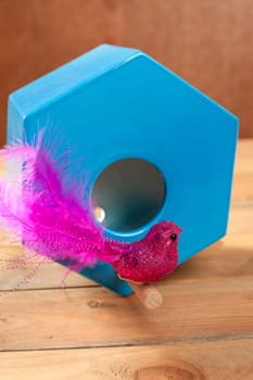 bird in blue nest house polygonal shape over wood