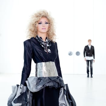 Black haute couture retro futurist couple in modern white hall with vampire inspiration